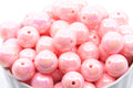 Pink iridescent beads in a white bowl