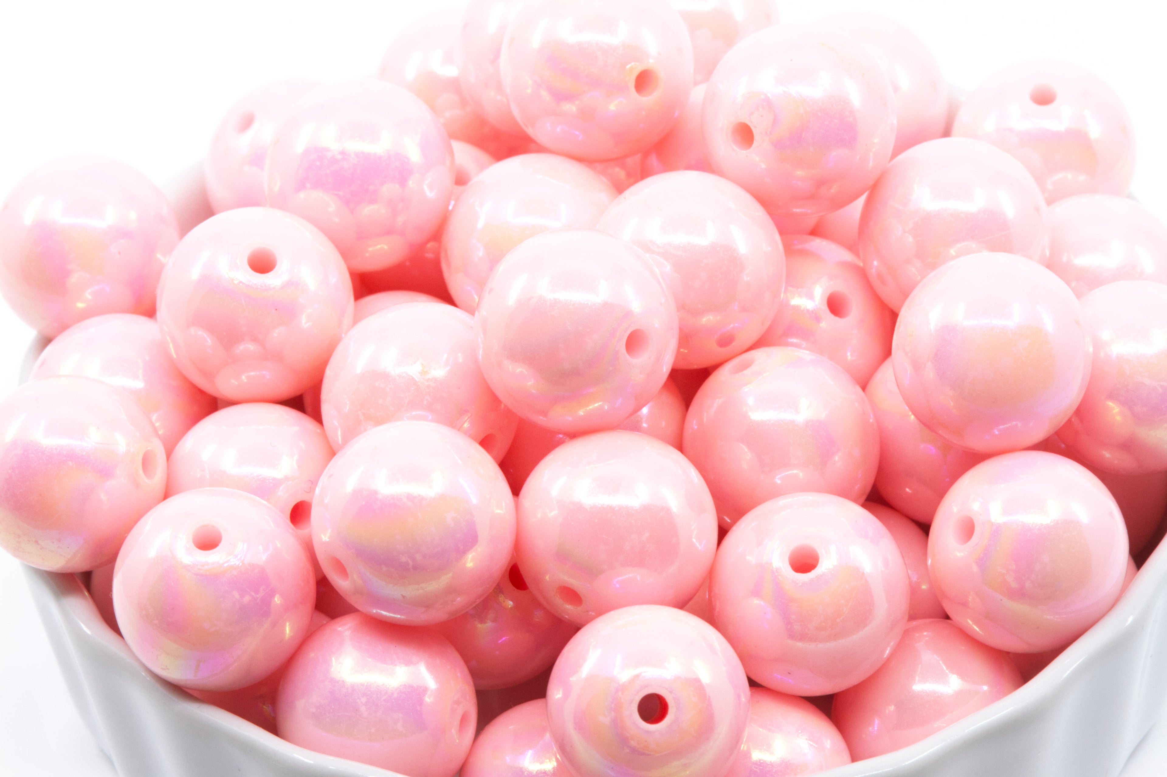 pink iridescent beads in a white bowl on a white background 