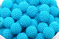 A close-up of many bright blue textured beads in a white bowl on a white background 