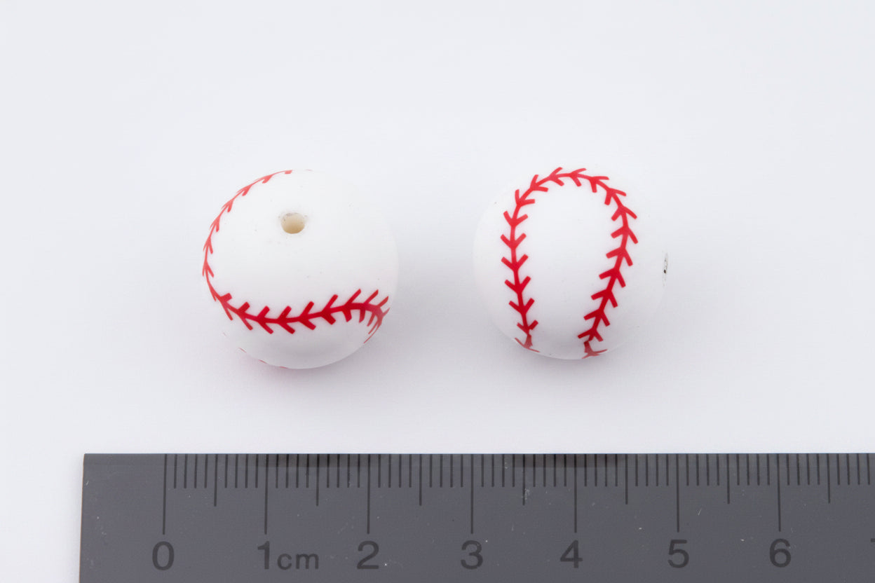 Two baseball beads with red stitching on a white background, measured against a ruler.