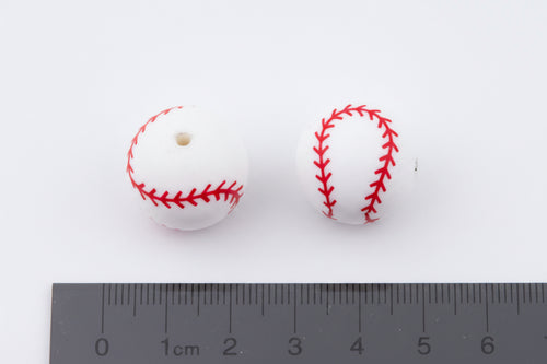 Two baseball beads with red stitching on a white background, measured against a ruler.