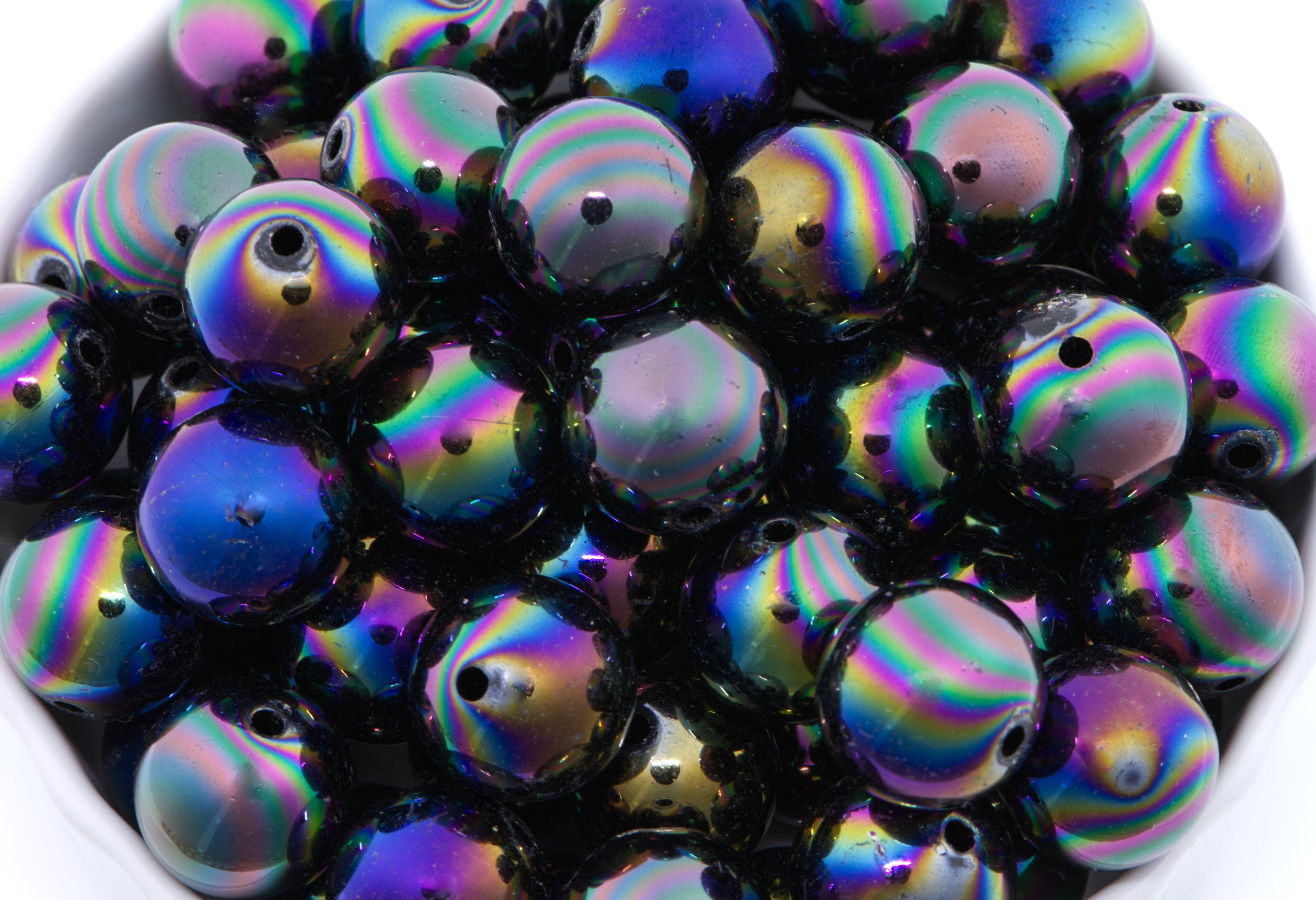 black iridescent beads in a white bowl with a white background