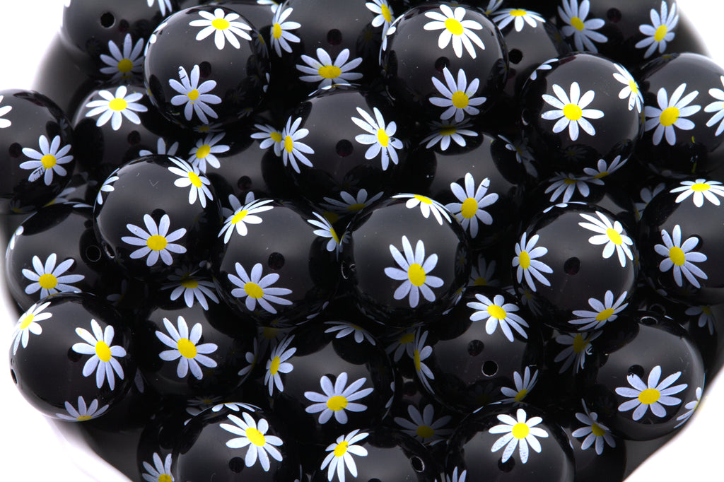 Black beads with white daisy patterns on a white background