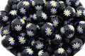 Black beads with white daisy patterns on a white background
