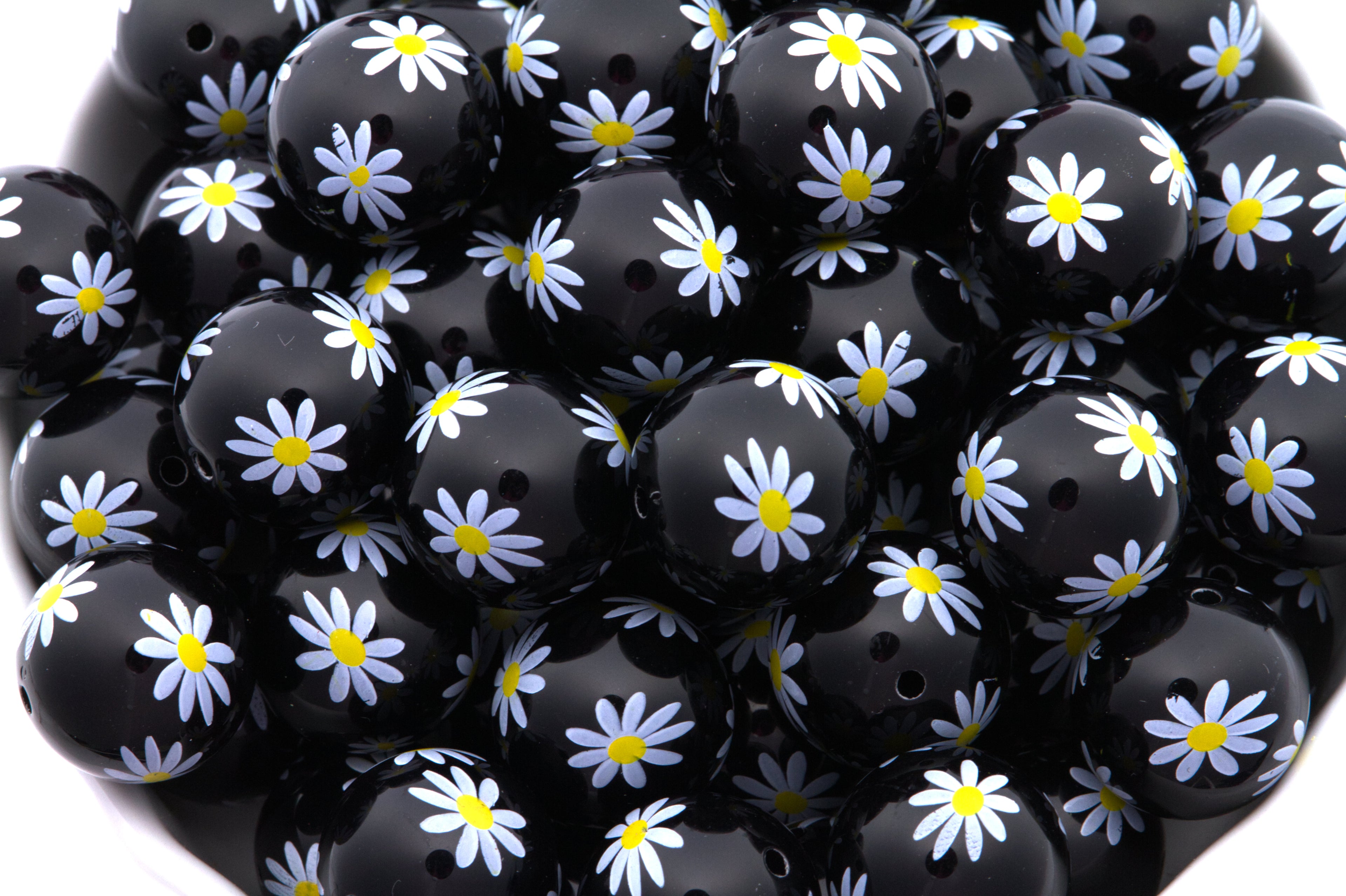 Black beads with white daisy patterns on a white background