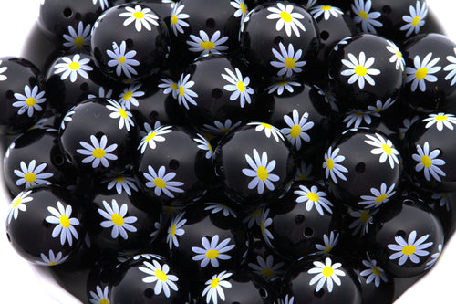 Black beads with white daisy patterns on a white background
