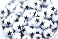 White beads with black star print, piled inside a white bowl against a white background.