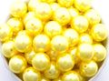 Yellow metallic beads in a white bowl on a white background