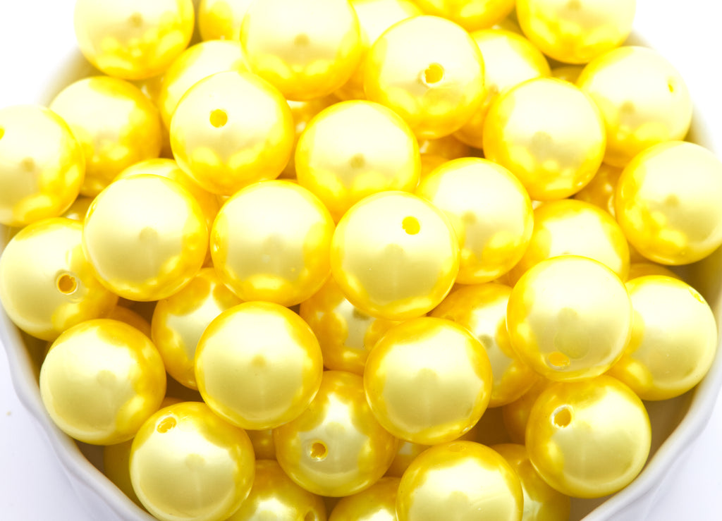 Close-up of yellow metallic beads in a white bowl
