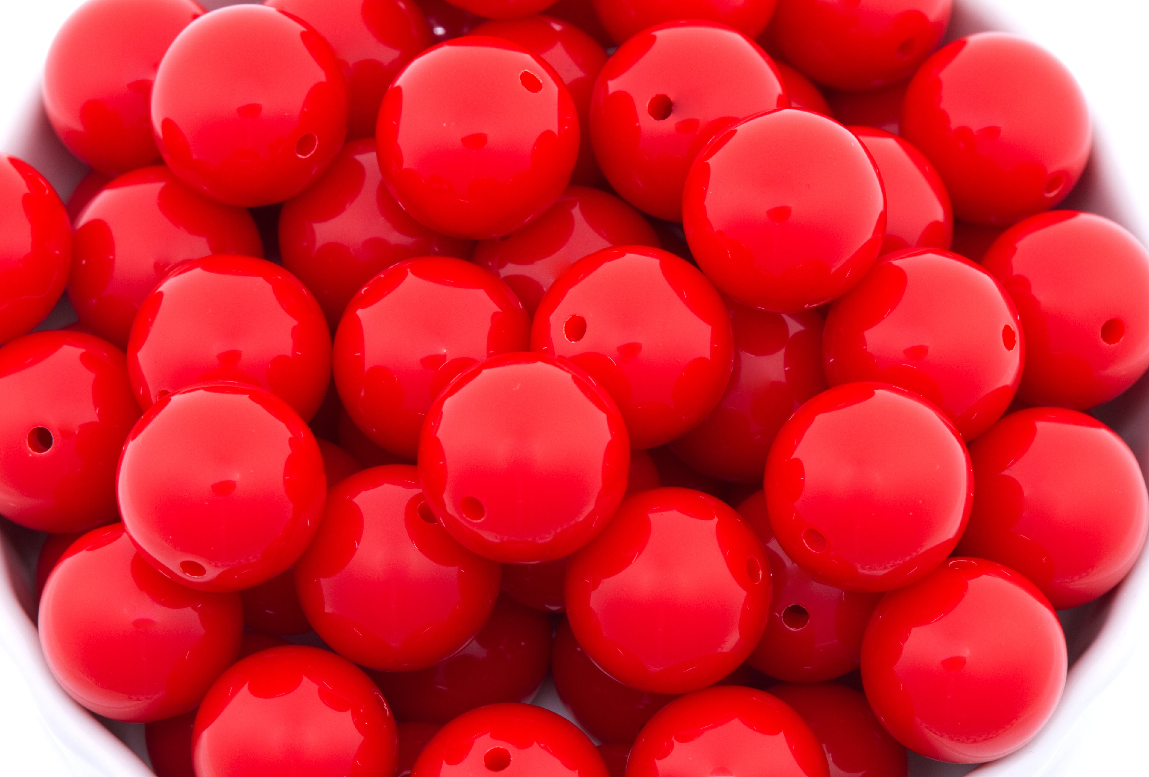red round beads in a white bowl on a white background