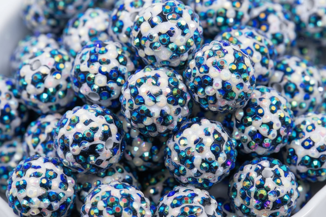 A close-up of many round black and white cheetah print rhinestone beads, piled inside a white bowl.