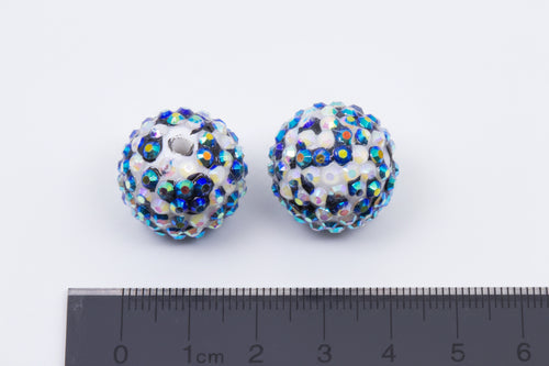 Two round rhinestone black and white cheetah print beads shown next to a black ruler for scale on a white background.