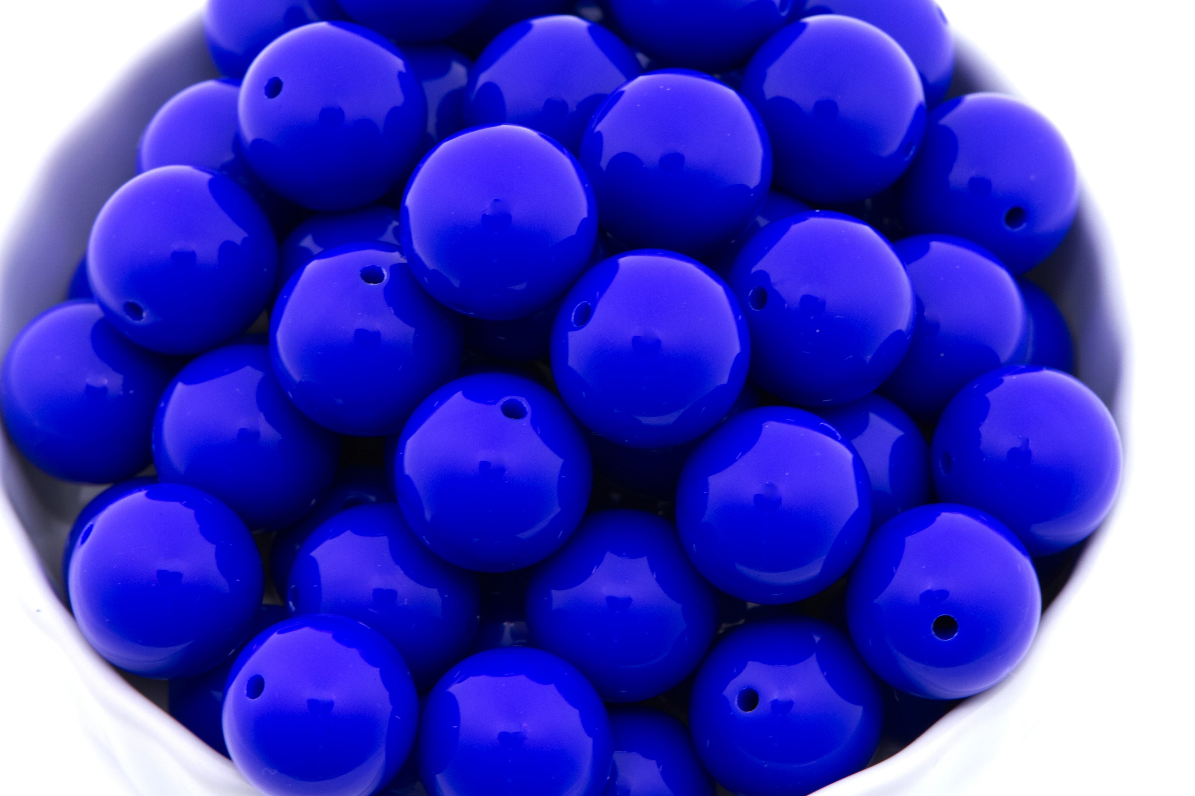 blue beads in a white bowl on a white background