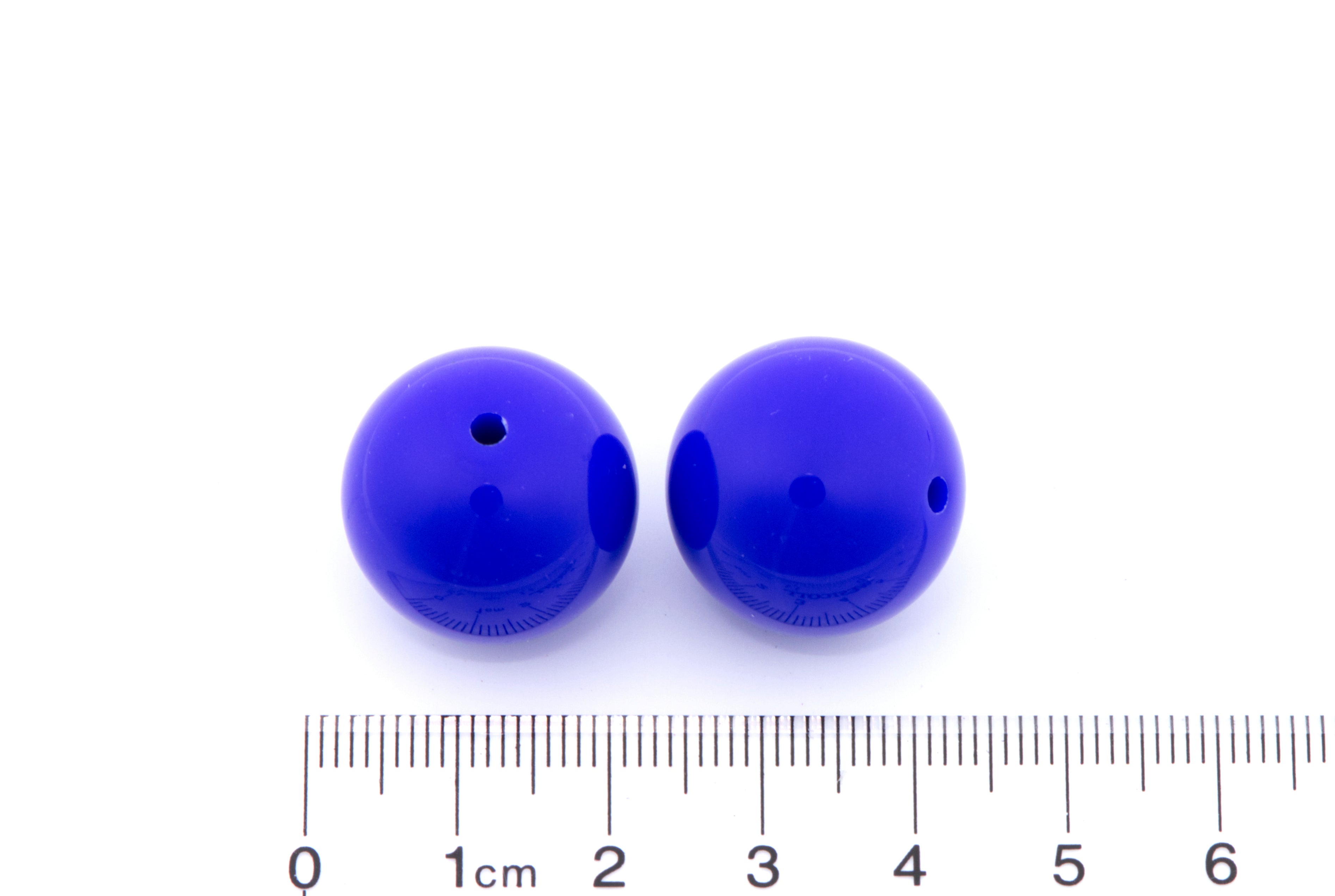 Two blue beads with a ruler for scale on a white background