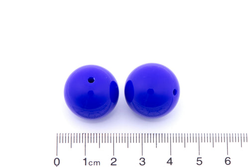Two blue beads with a ruler for scale on a white background