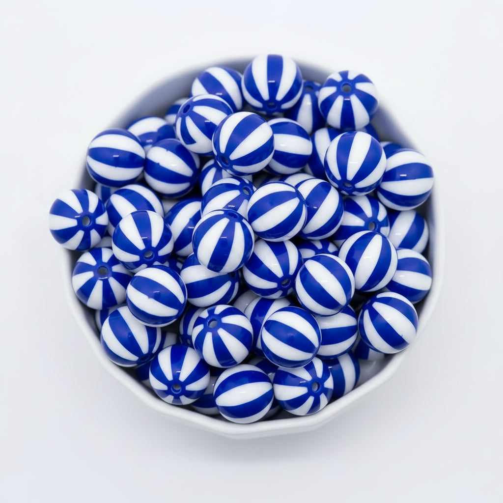 A pile of round  blue and white beach ball striped beads, photographed on a clean white background.