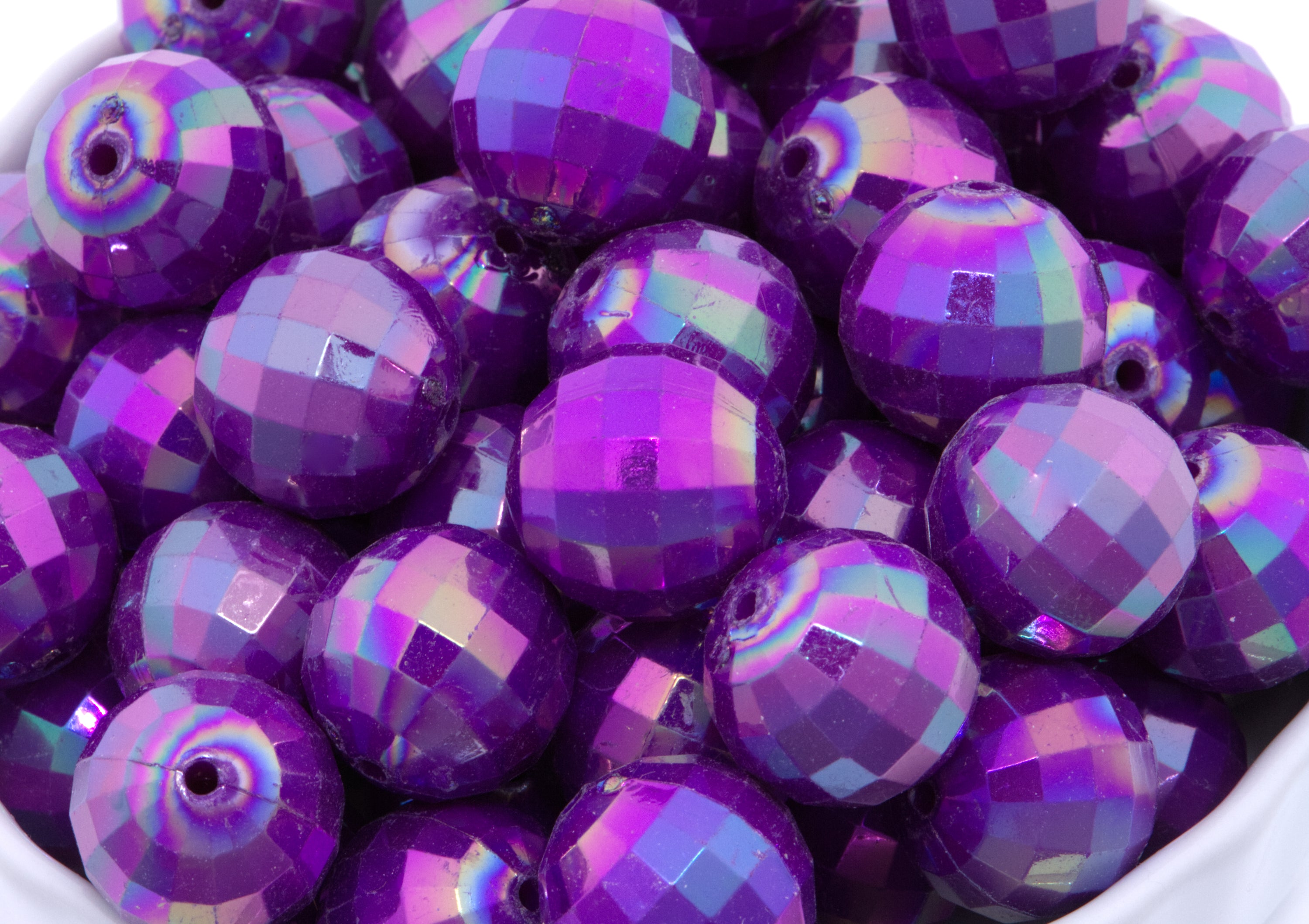 Purple faceted beads in a white bowl on a white background