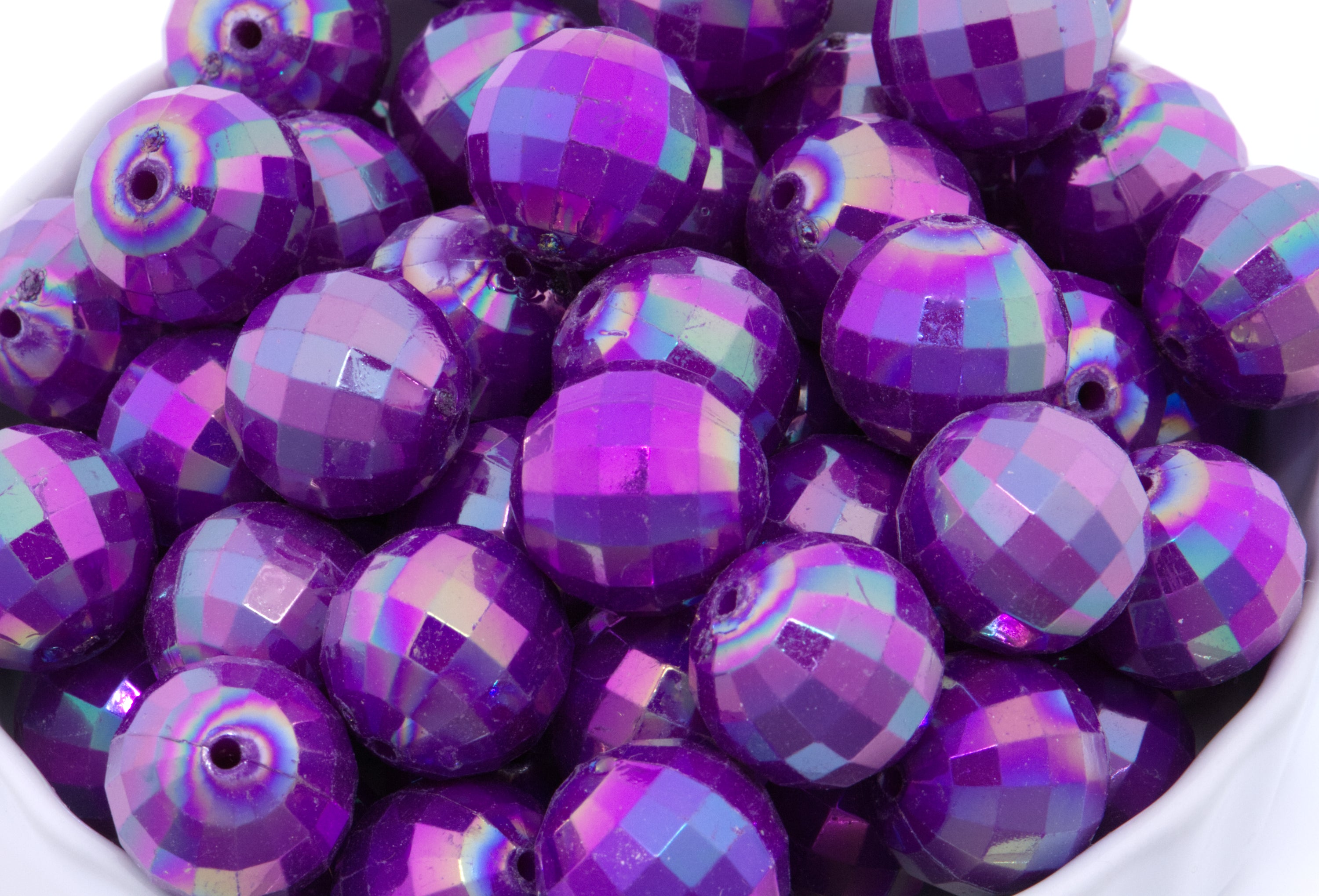 purple faceted beads in a white bowl on a white background
