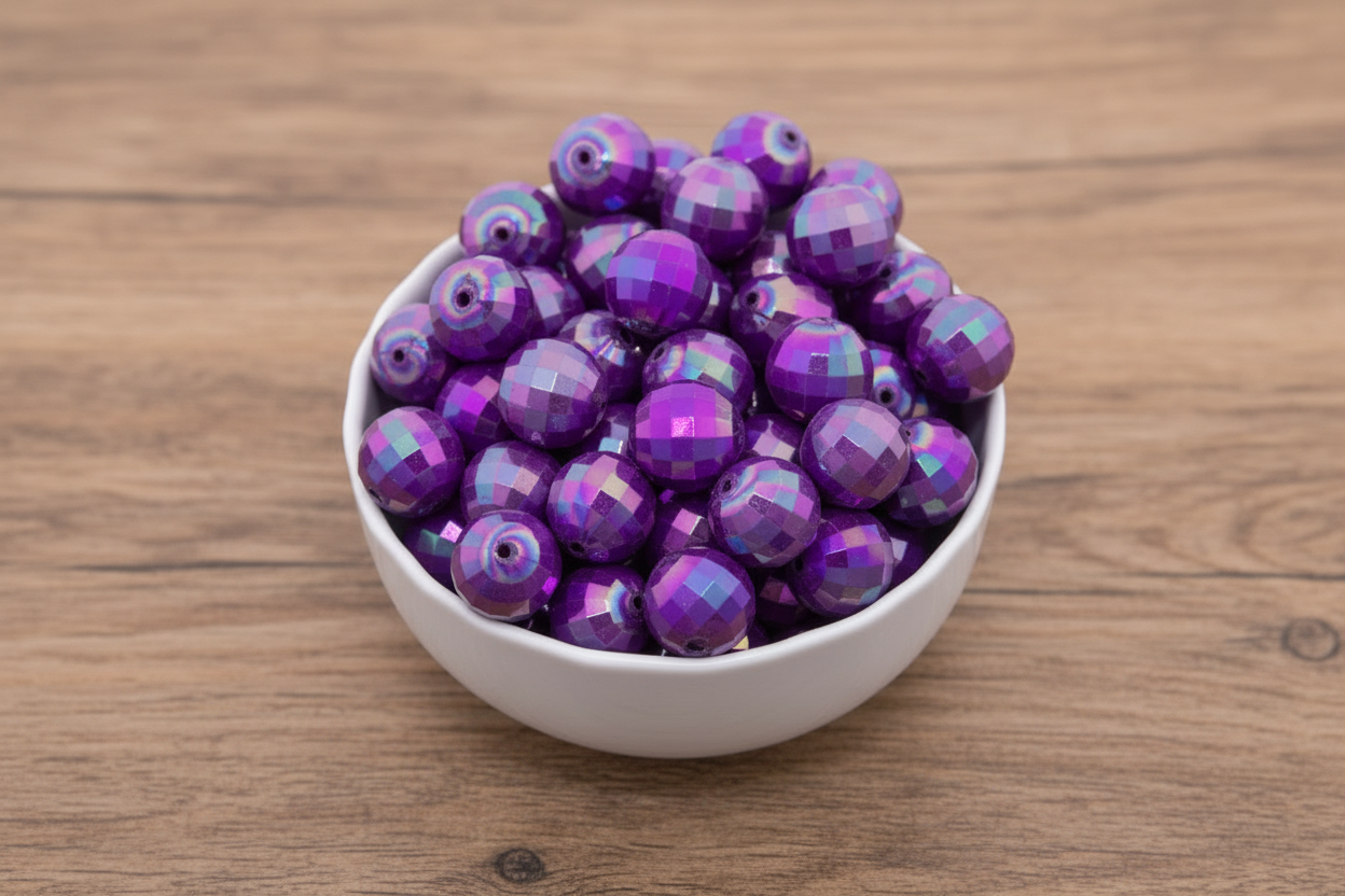 Purple faceted beads in a white bowl on a wooden surface