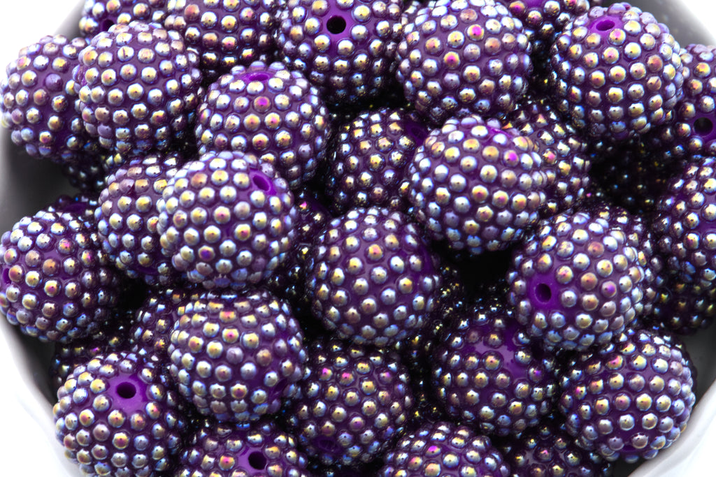 Close-up of purple beads with AB coating in a white bowl on a white background 