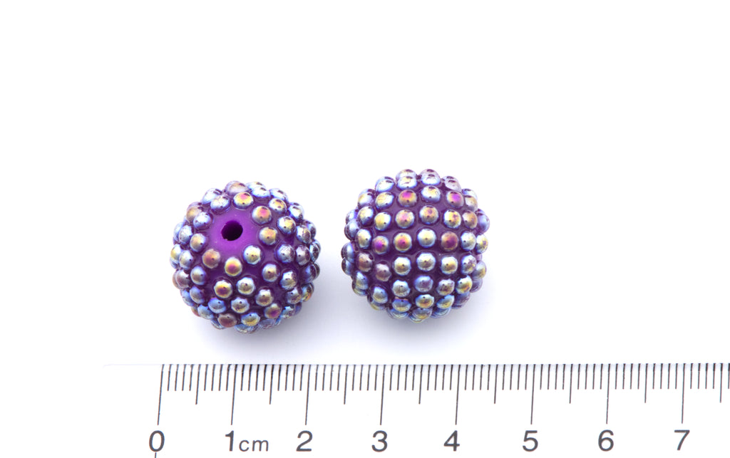 Purple beads with AB coating on a white background with a ruler for scale.