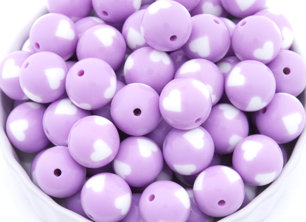 Purple beads with white heart patterns on a white background