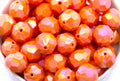 orange faceted beads in a white bowl on a white background