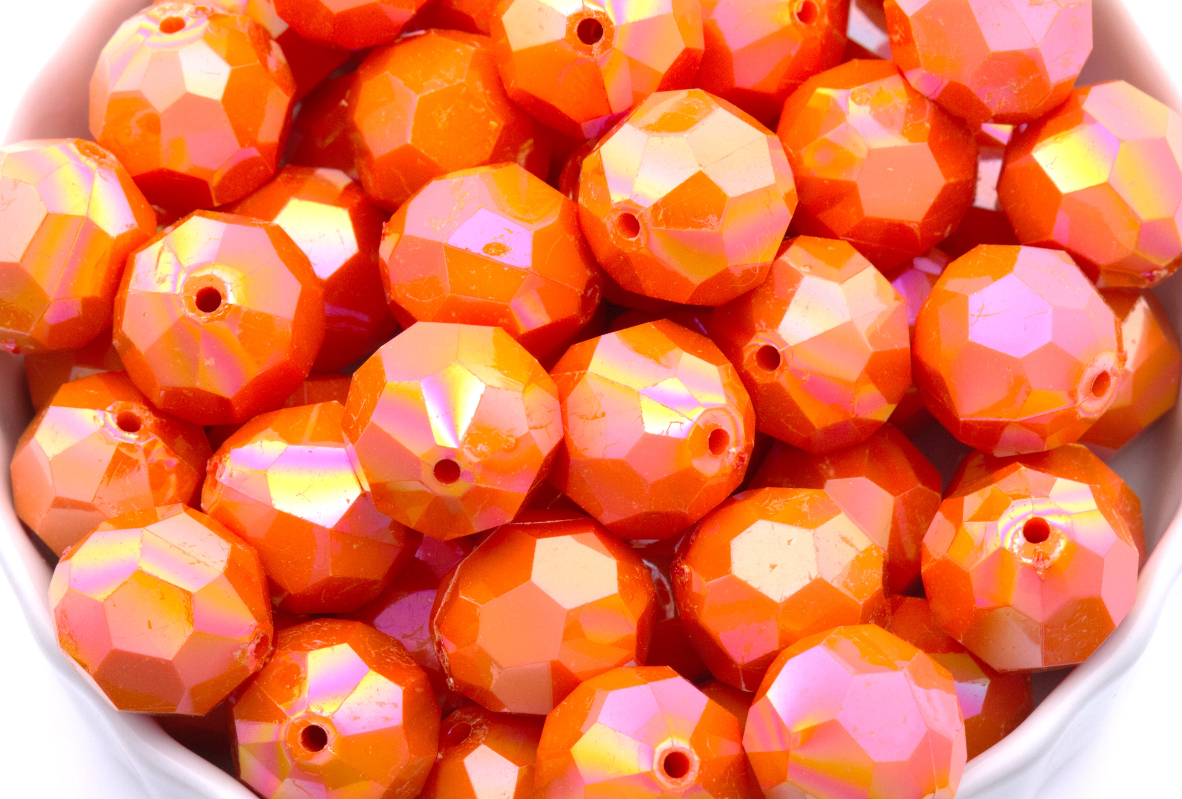 orange faceted beads in a white bowl on a white background