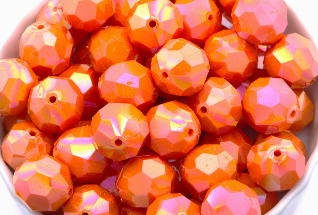orange faceted beads in a white bowl on a white background