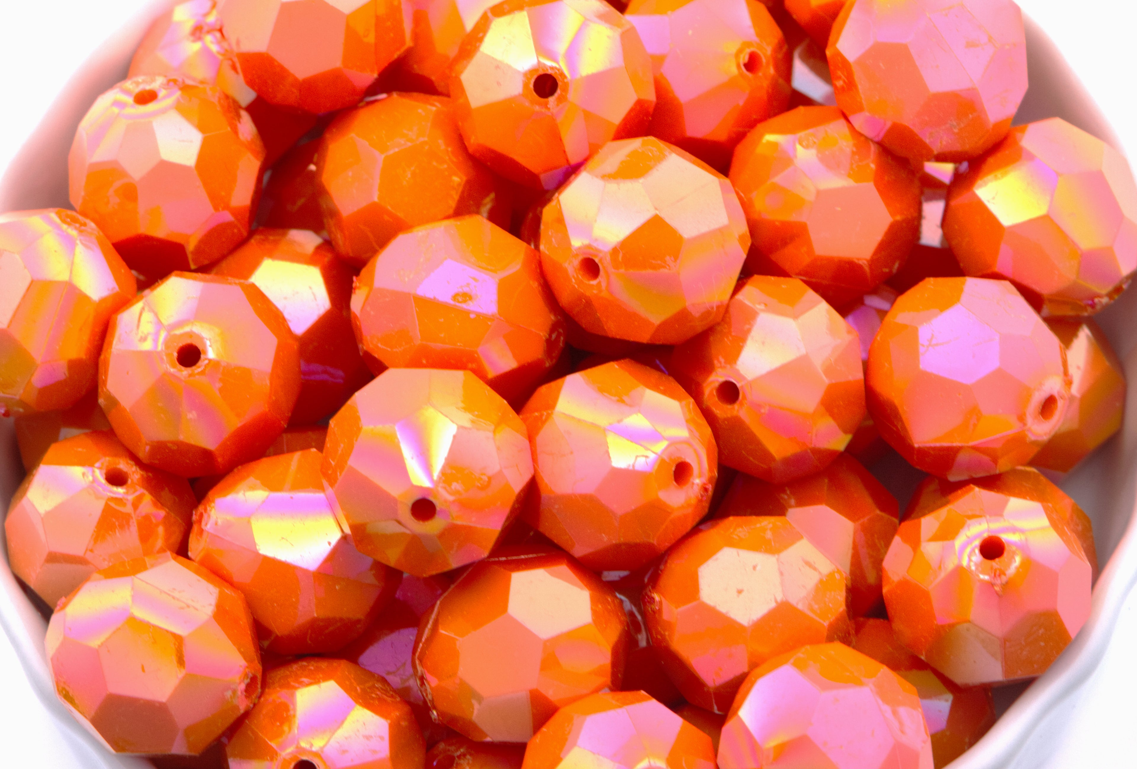 orange faceted beads in a white bowl on a white background
