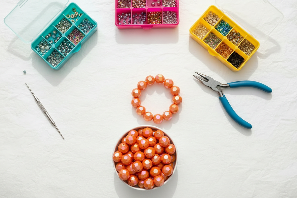 orange faceted Beads, pliers, and bead storage containers on a white surface