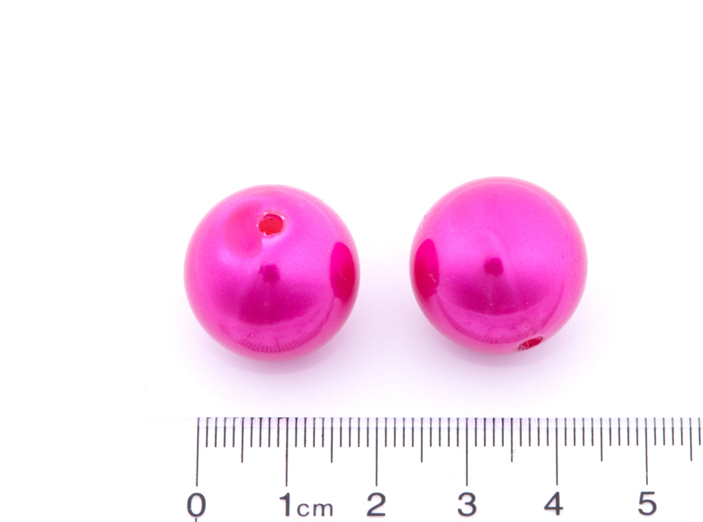 Two shiny pink bubblegum beads with a hole in the center, shown next to a cm ruler for scale on a white background.