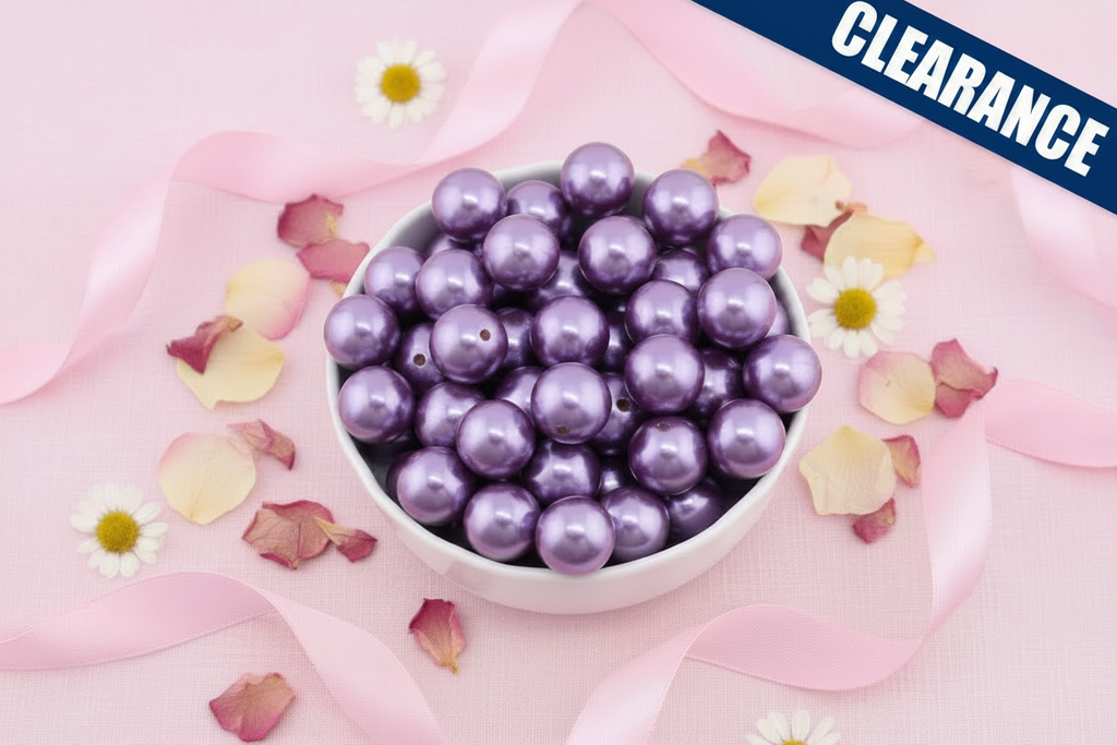 Purple metallic beads in a white bowl surrounded by flowers and ribbons on a pink background. clearance label on the top right corner.