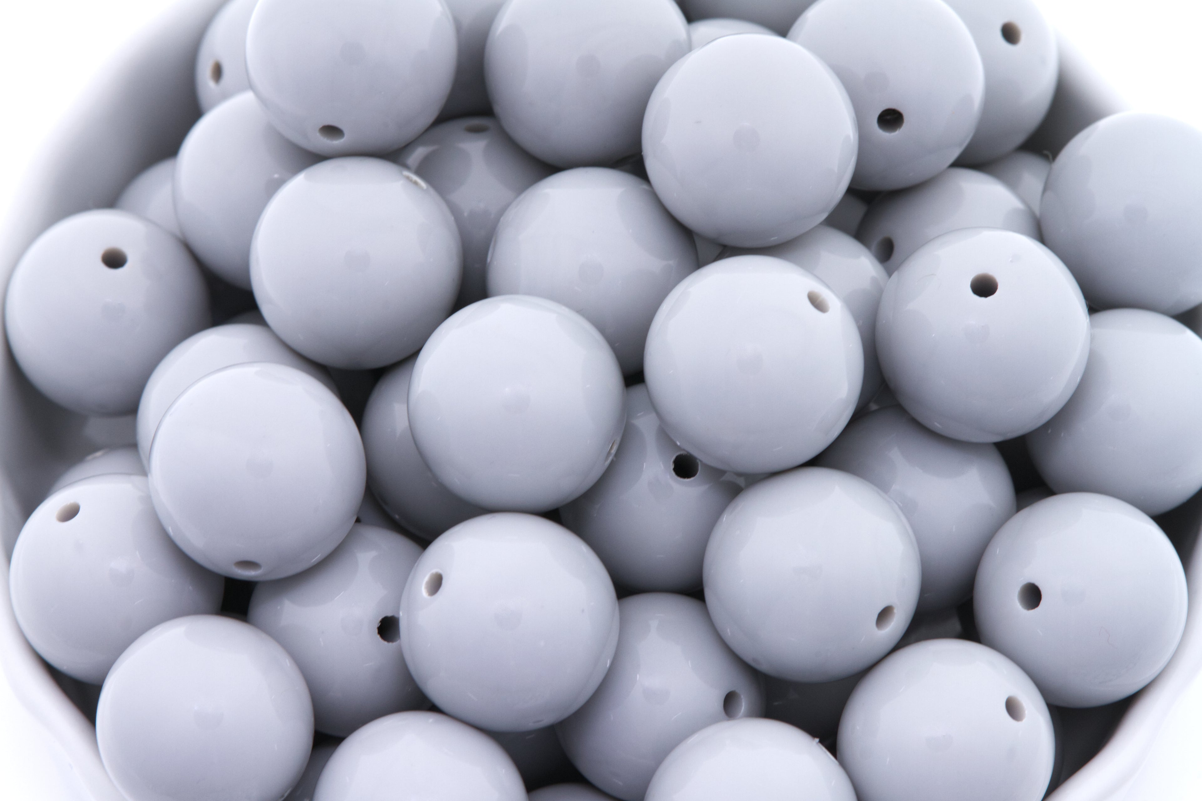 gray beads in a white bowl on a white background