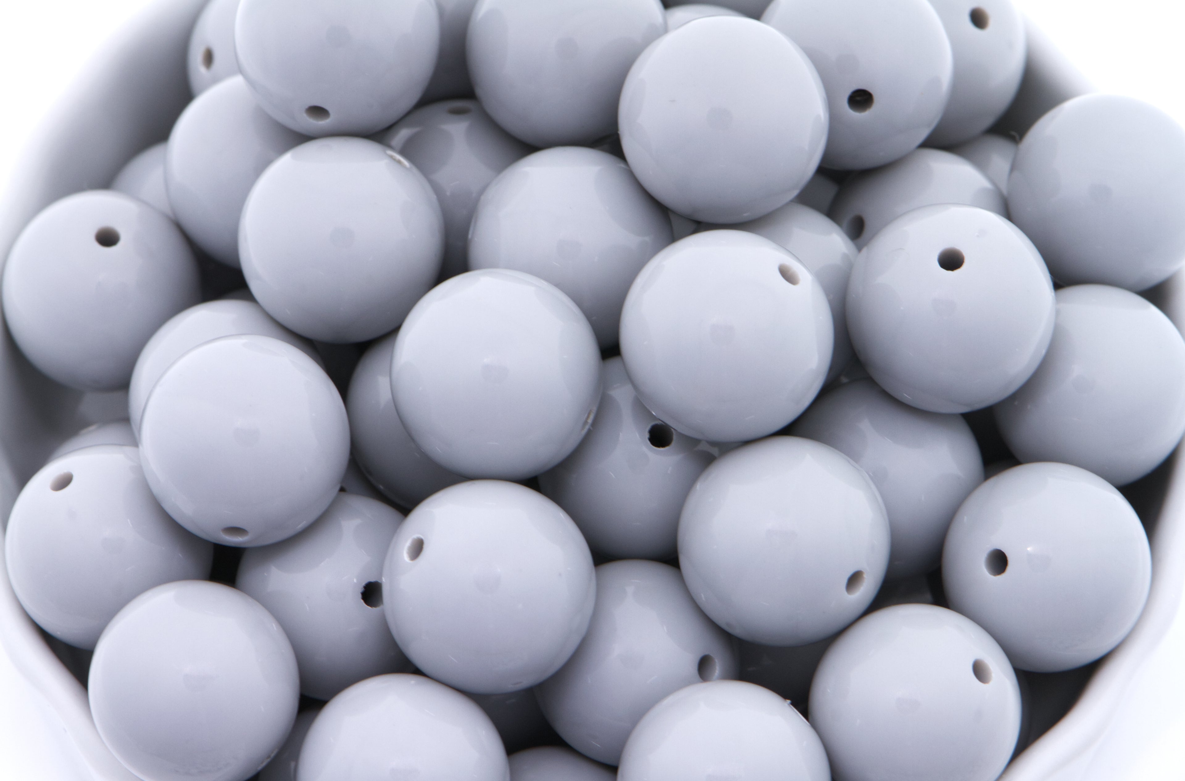 gray beads in a white bowl on a white background 