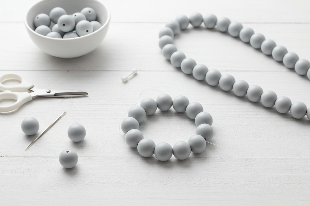 Gray beads shown as bracelets and necklace with scissors, and a bracelet on a white surface