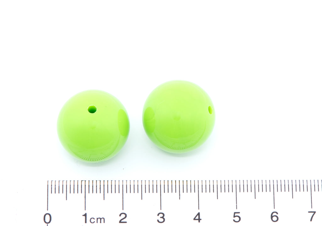 Two green beads with a ruler for scale on a white background