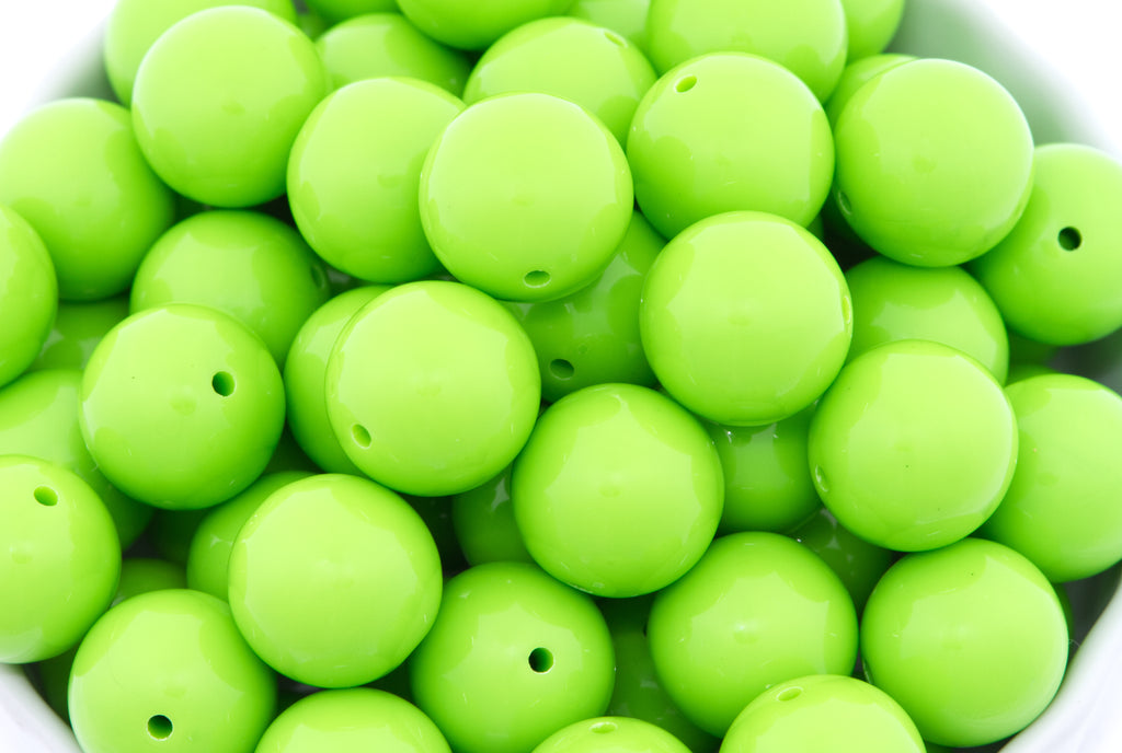 green beads in a white bowl on a white background