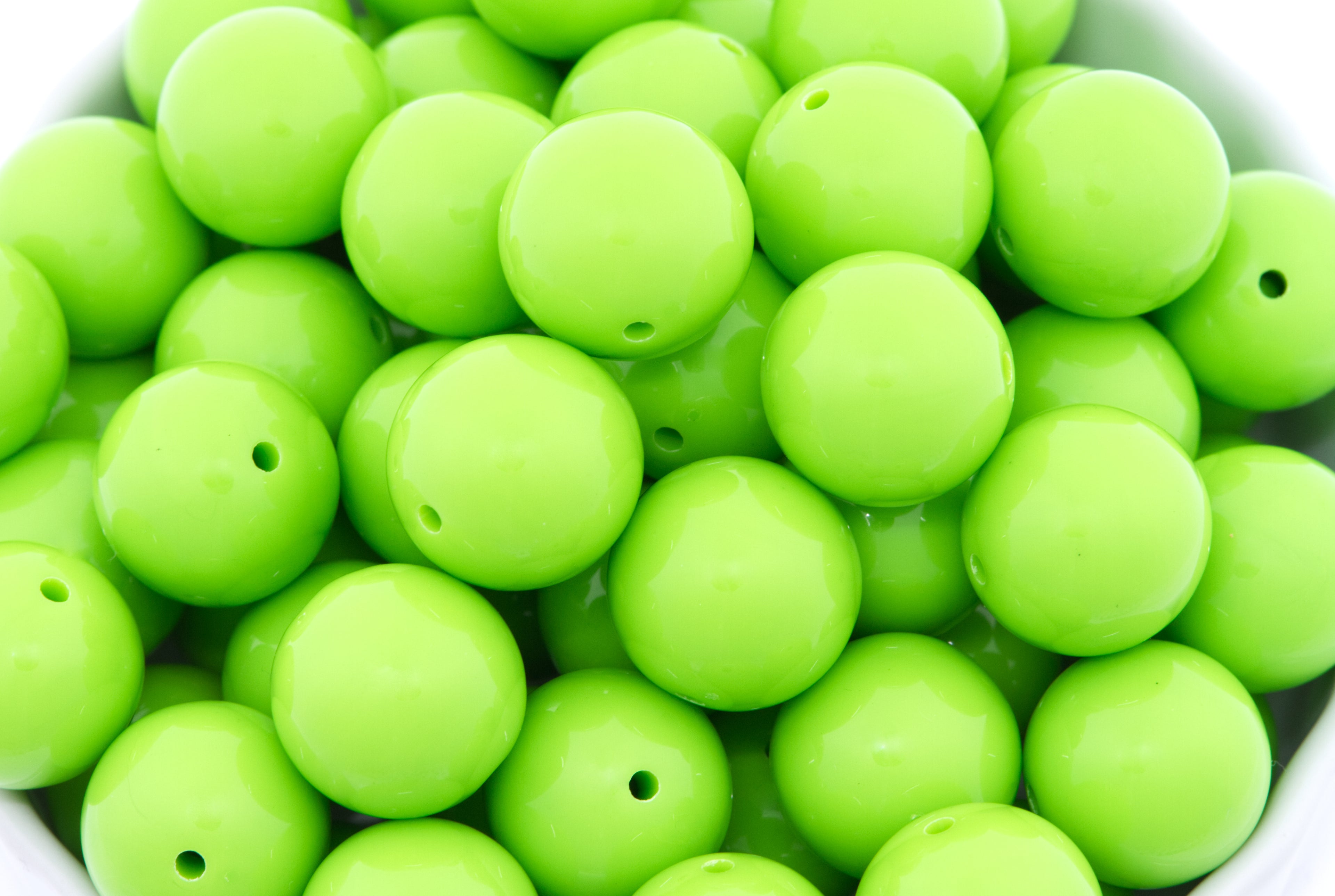 green beads in a white bowl on a white background
