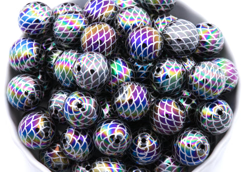 A pile of round iridescent beads with a mermaid scale pattern shown in a close-up view inside a white bowl on a white background. 