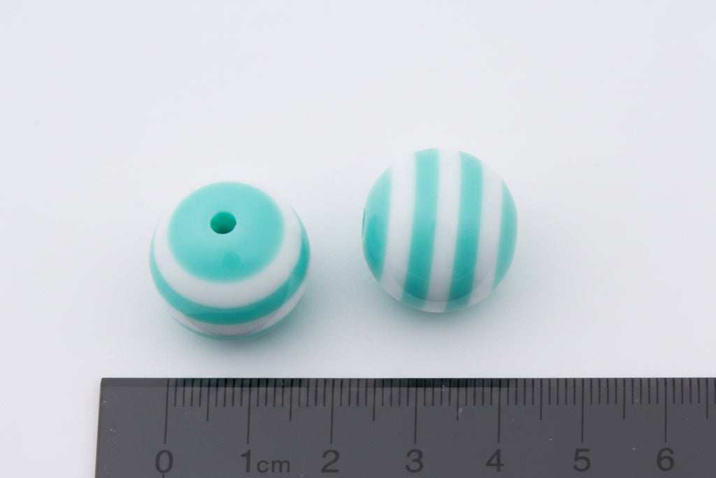 Two round mint green and white striped beads shown next to a black ruler for scale on a white background.