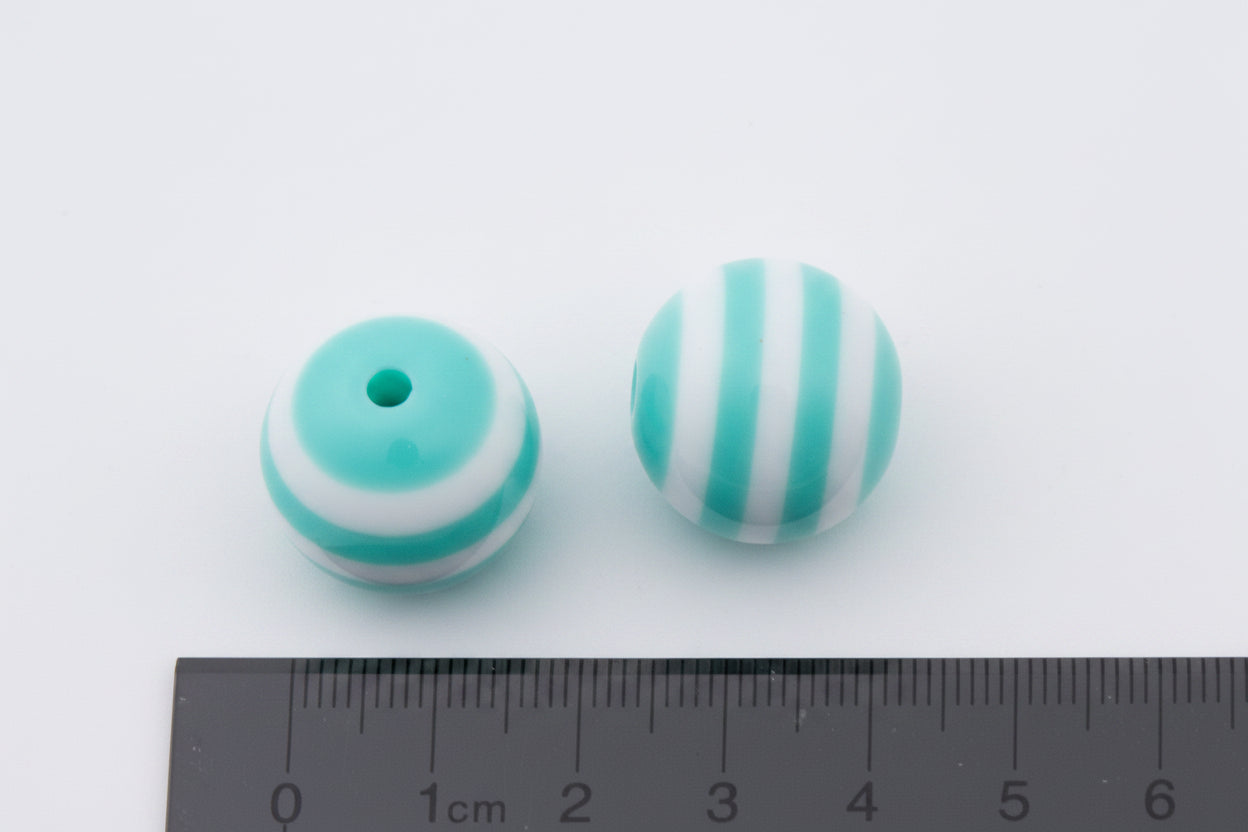 Two round mint green and white striped beads shown next to a black ruler for scale on a white background.