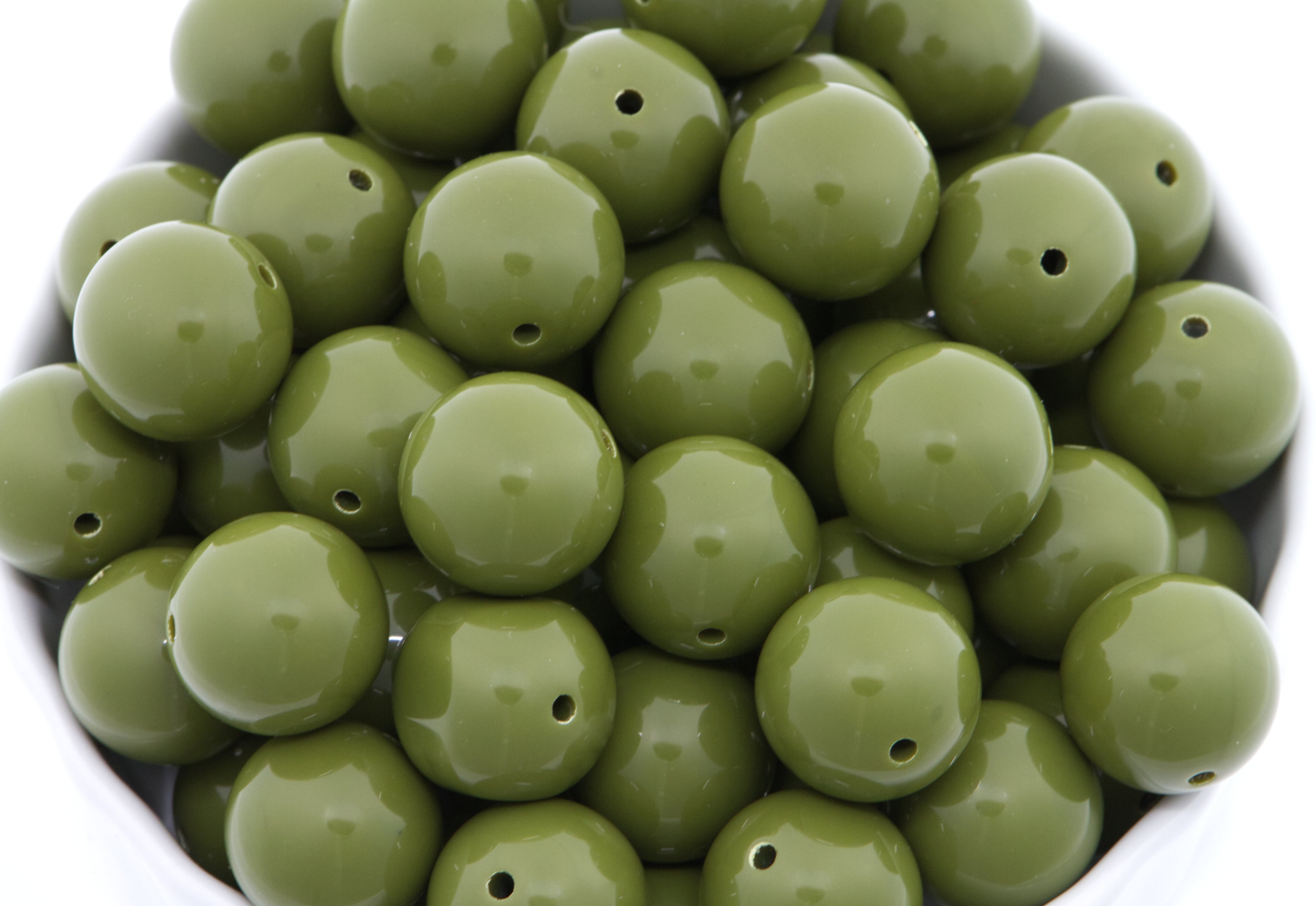 green beads in a white bowl on a white background