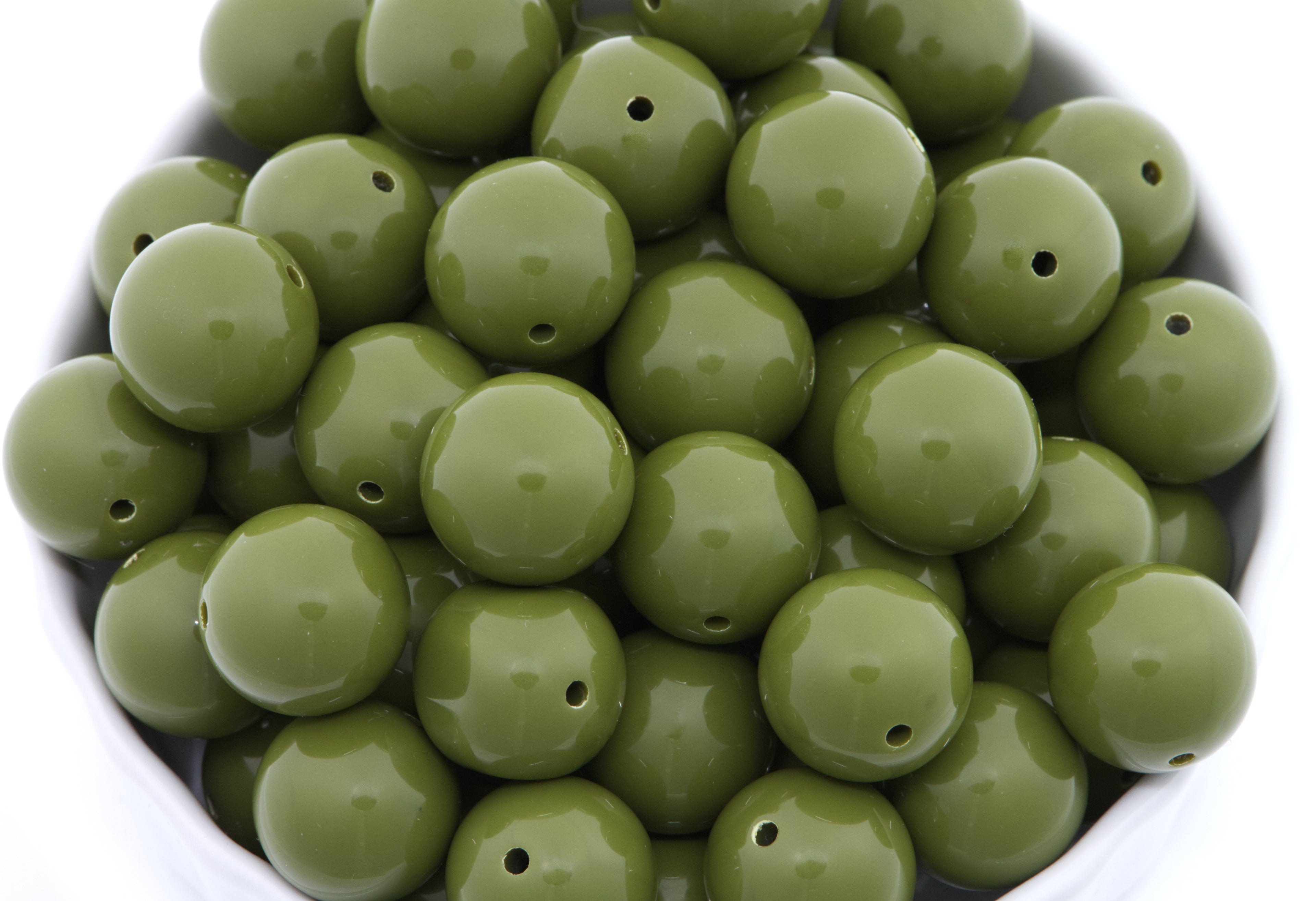 Green beads in a white bowl on a white background