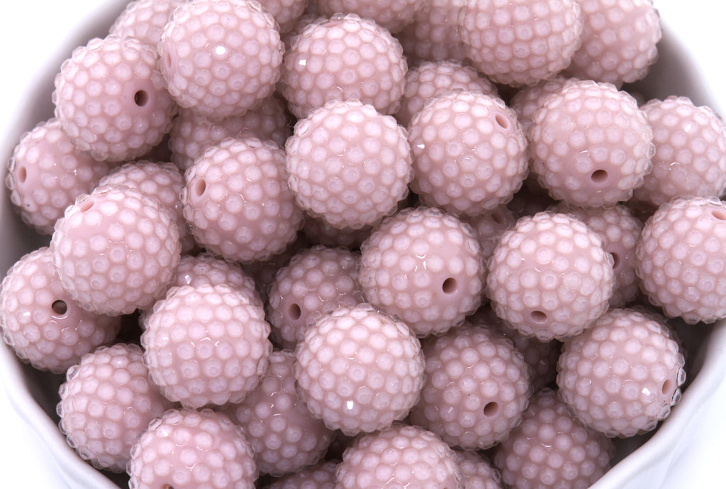 Close-up of pink rhinestone beads in a white bowl