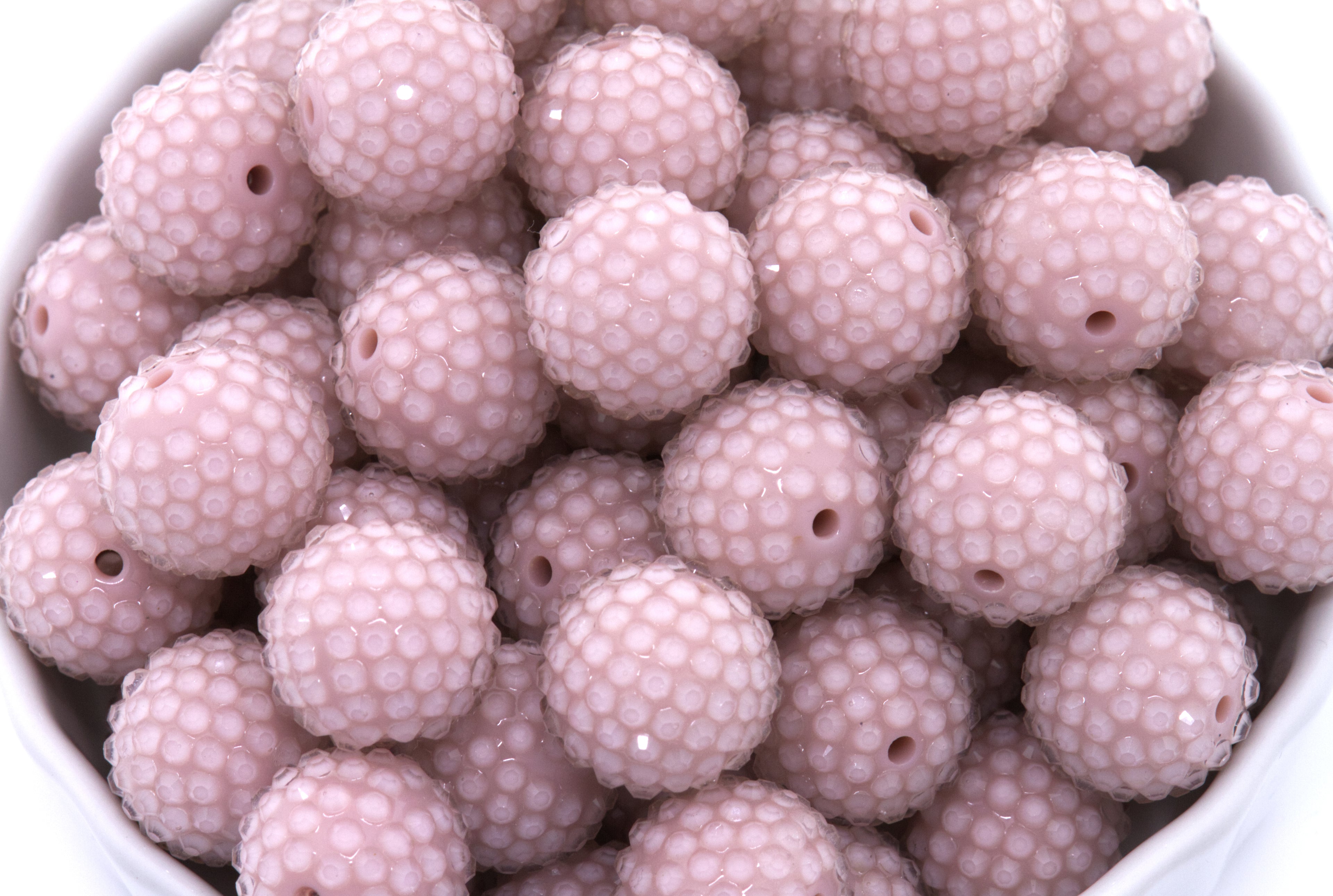 Close-up of pink rhinestone beads in a white bowl