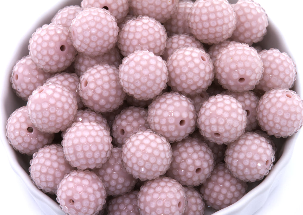 Close-up of pink rhinestone beads in a white bowl
