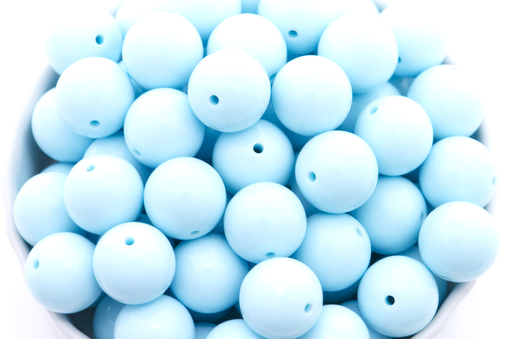 Light blue beads in a white bowl on a white background 