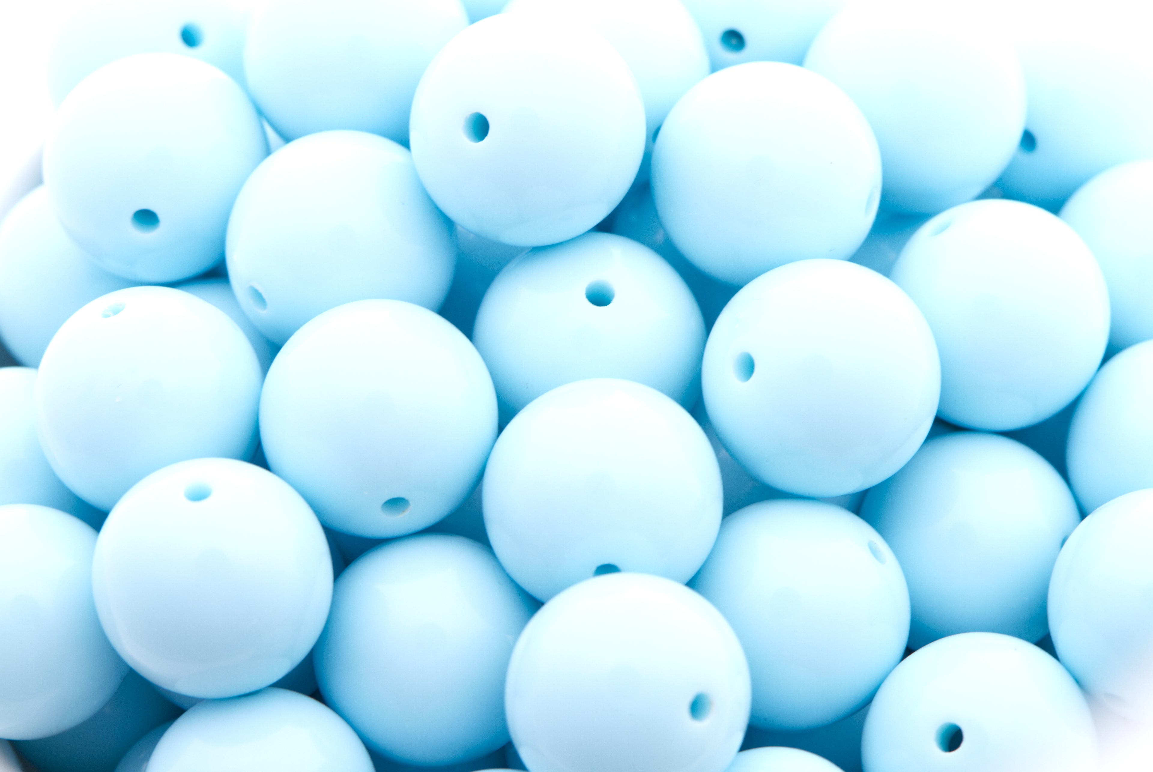 light blue beads  in a white bowl with a white background