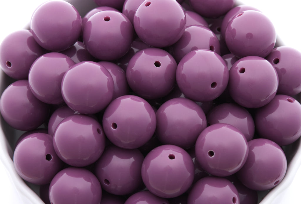 purple beads in a white bowl on a white background